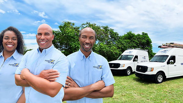 Three professionals in light blue branded shirts stand confidently with crossed arms, flanked by service vans under a clear blue sky.