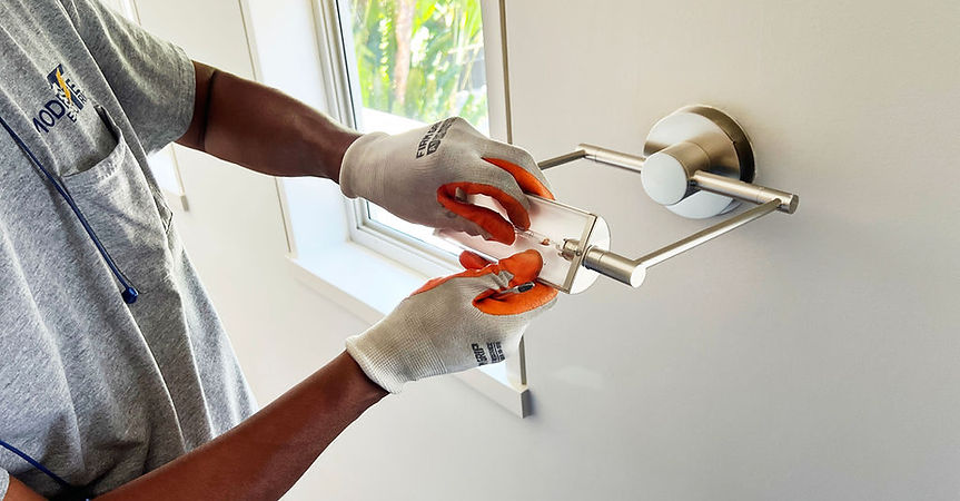 A man repairs a light switch mounted on a wall, focusing intently on the task at hand.